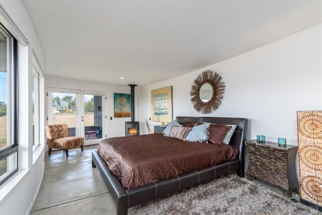 bedroom with a wood stove, concrete flooring, recessed lighting, french doors, and access to exterior