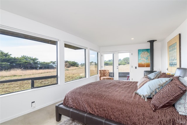 bedroom with access to outside, a wood stove, carpet floors, french doors, and baseboards