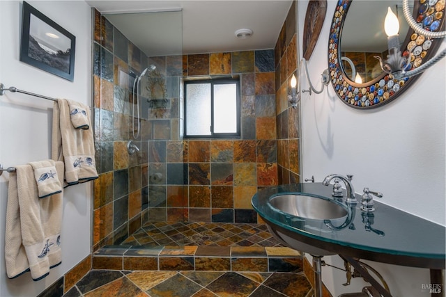 bathroom featuring a walk in shower, stone tile floors, and a sink
