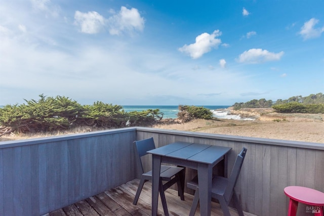 wooden terrace featuring a beach view and a water view