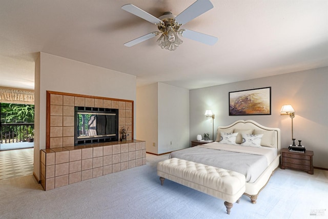 bedroom with a tiled fireplace, carpet flooring, baseboards, and ceiling fan