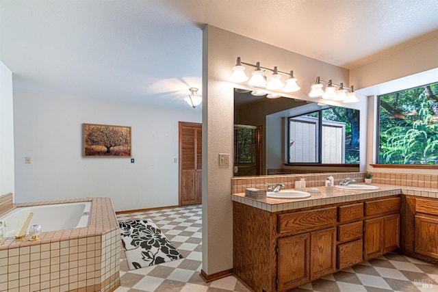 full bathroom featuring a sink, tile patterned floors, double vanity, and a garden tub