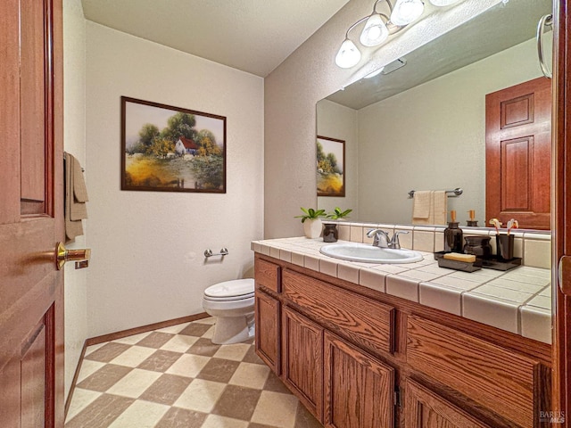 half bathroom with toilet, tile patterned floors, vanity, and baseboards