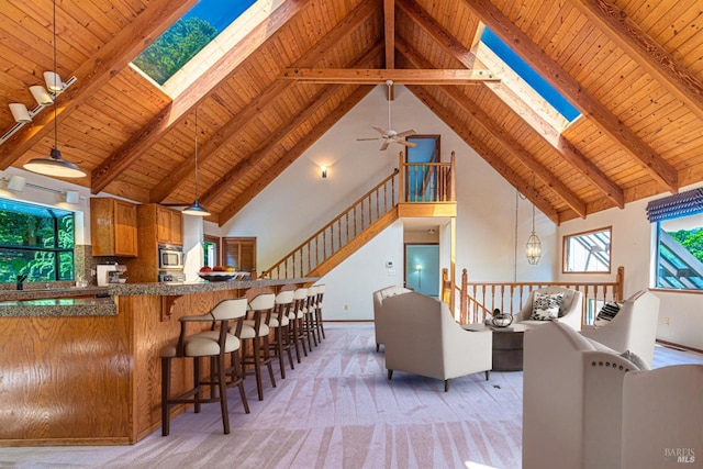 living room with a skylight, high vaulted ceiling, beam ceiling, and wood ceiling