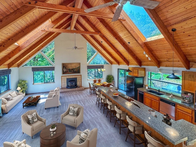living room with wood ceiling, a ceiling fan, beam ceiling, and plenty of natural light