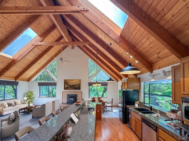 kitchen with open floor plan, a skylight, light wood finished floors, and black appliances