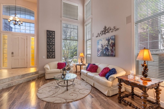 living room featuring a wealth of natural light, a high ceiling, a notable chandelier, and hardwood / wood-style flooring