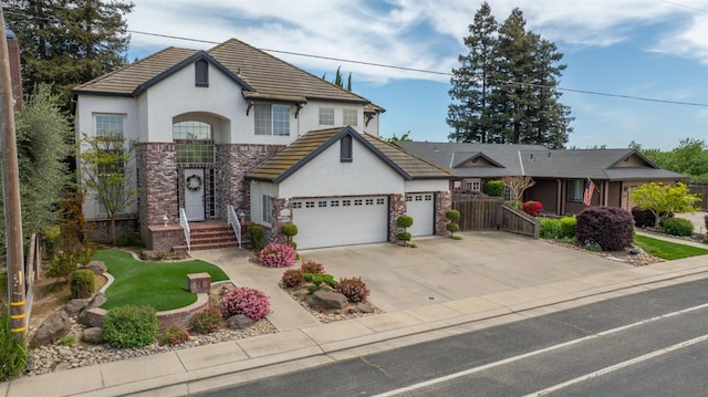 view of front of property with fence, stucco siding, a tiled roof, an attached garage, and driveway