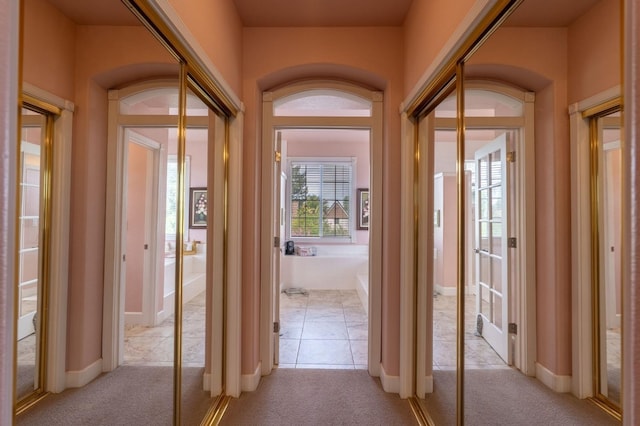 hall featuring baseboards and light carpet