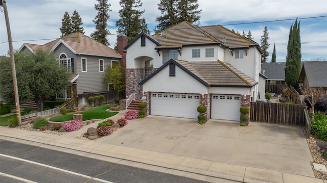 view of front of property with fence, stucco siding, an attached garage, driveway, and a tile roof
