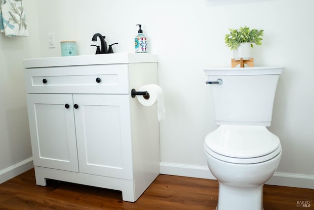 bathroom with toilet, baseboards, and vanity
