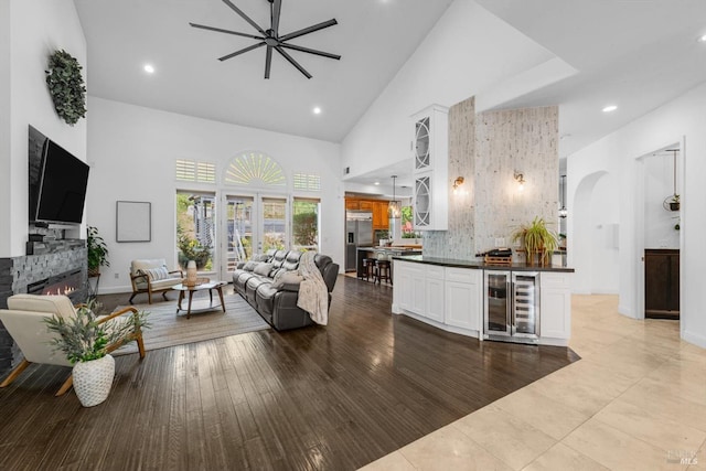 living area featuring arched walkways, a fireplace, recessed lighting, high vaulted ceiling, and beverage cooler