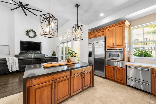 kitchen with brown cabinets, open floor plan, light tile patterned floors, a warming drawer, and appliances with stainless steel finishes
