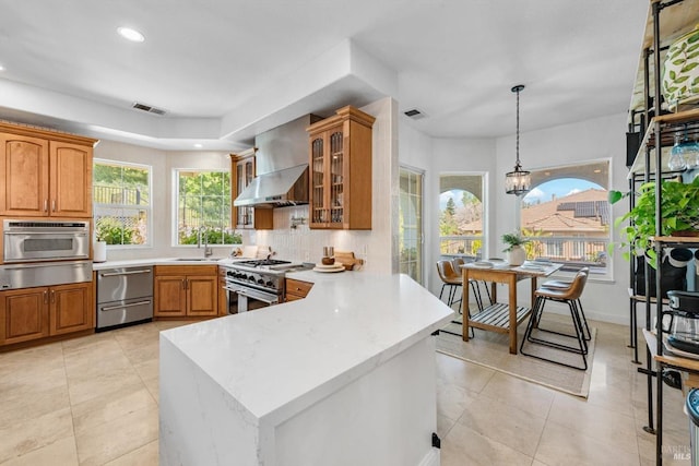 kitchen featuring stainless steel appliances, visible vents, a warming drawer, wall chimney exhaust hood, and a peninsula