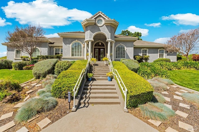 view of front facade featuring french doors, stucco siding, and stairs