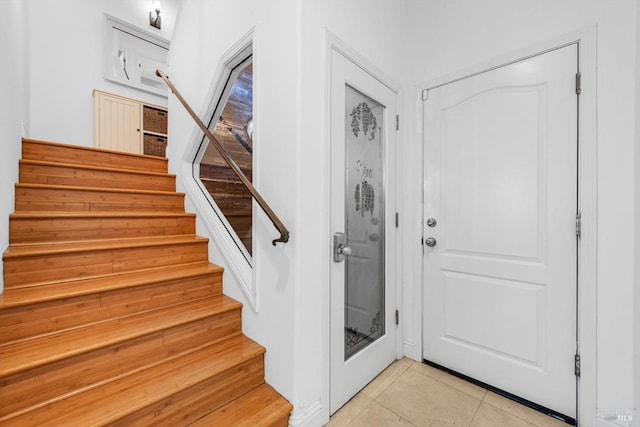 foyer featuring light tile patterned flooring and stairs