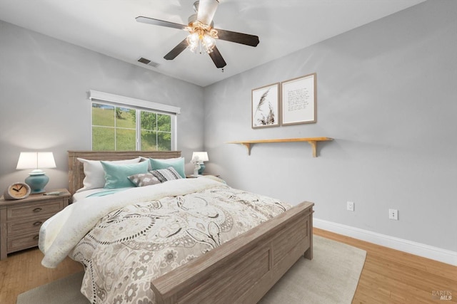 bedroom with light wood-style flooring, visible vents, a ceiling fan, and baseboards