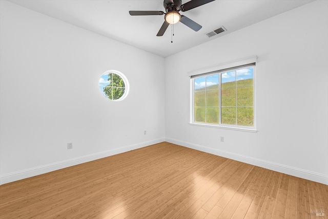 spare room featuring baseboards, light wood-style flooring, visible vents, and a wealth of natural light