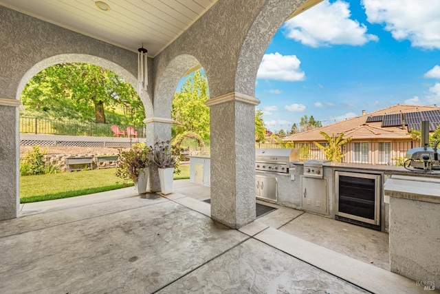 view of patio / terrace featuring an outdoor kitchen, fence, wine cooler, and a grill