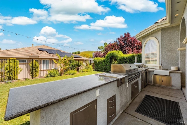 view of patio with an outdoor kitchen, area for grilling, a sink, and a fenced backyard