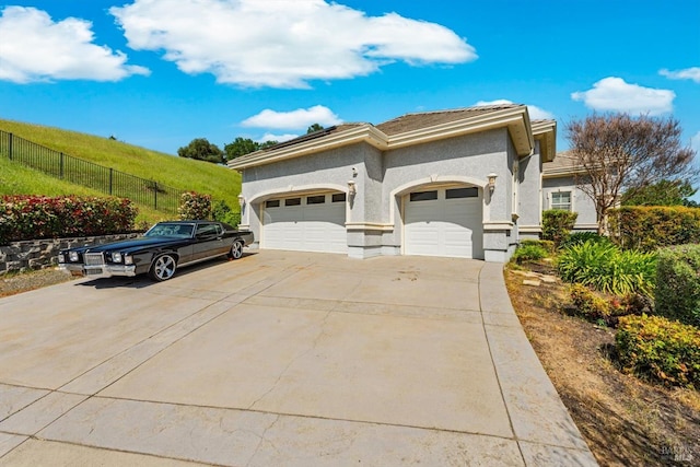exterior space with concrete driveway, fence, stucco siding, and a garage