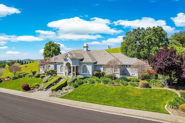 view of front of home with a tile roof, a front lawn, and stucco siding