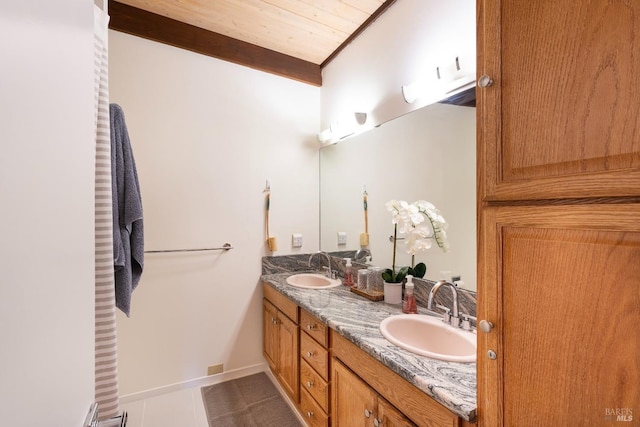 full bathroom with tile patterned flooring, double vanity, baseboards, and a sink