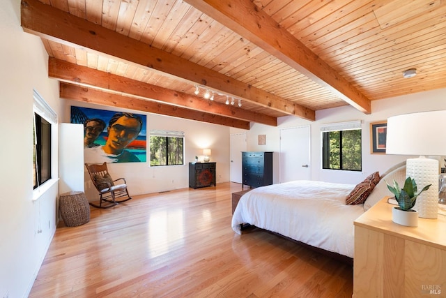 bedroom featuring beamed ceiling, light wood finished floors, multiple windows, and wooden ceiling