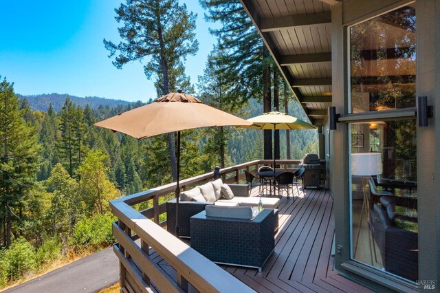 deck featuring grilling area, a forest view, and outdoor dining area