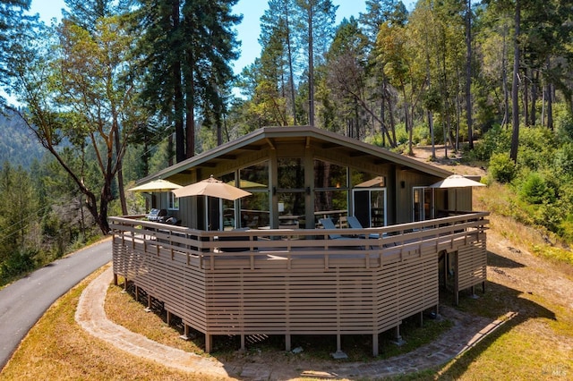 rear view of house with a wooded view and a wooden deck