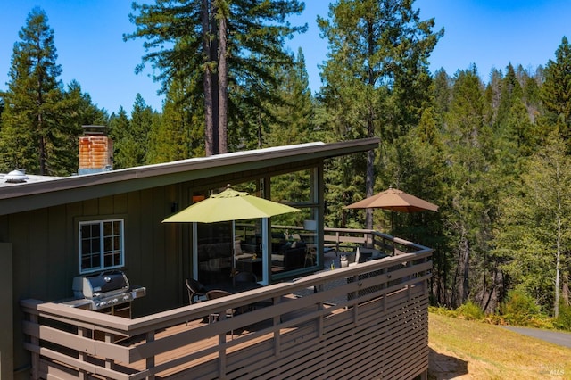 deck featuring a wooded view and area for grilling