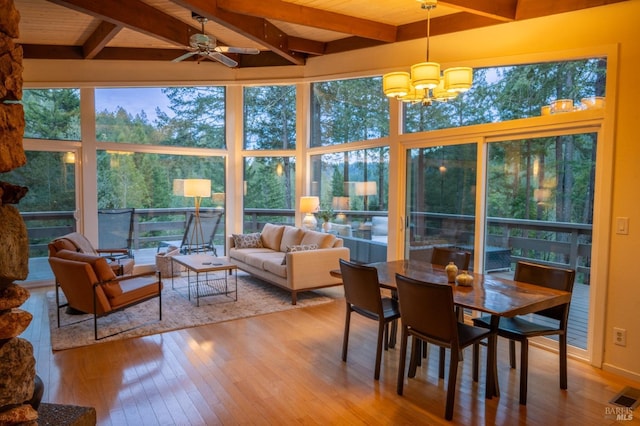 sunroom / solarium with a healthy amount of sunlight, beamed ceiling, wood-type flooring, and visible vents