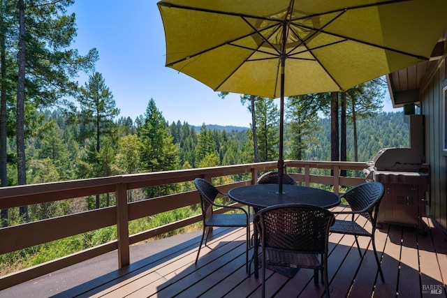 deck with grilling area and a view of trees