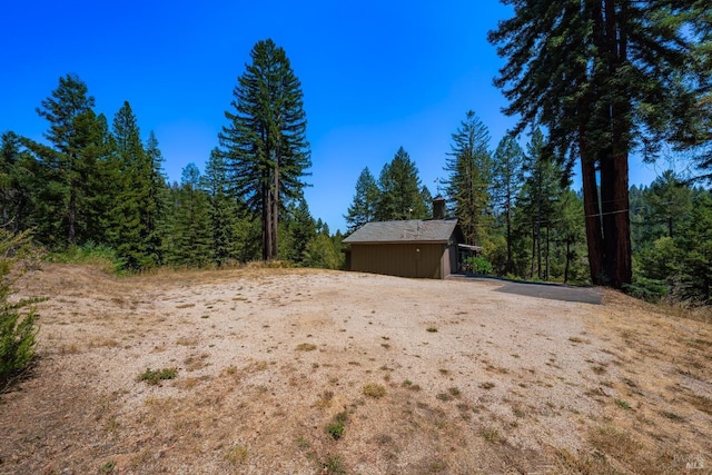 view of yard featuring a wooded view and an outdoor structure