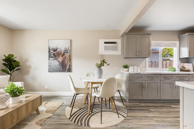 kitchen featuring a wall mounted air conditioner, gray cabinetry, dark wood-style floors, and baseboards