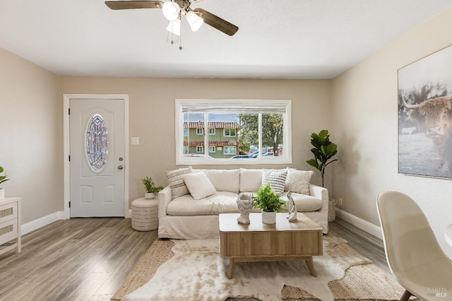 living room with baseboards, a ceiling fan, and wood finished floors