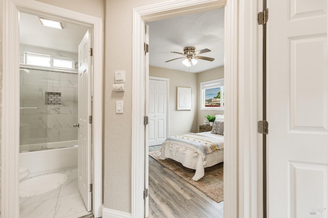 bathroom featuring ceiling fan, bathtub / shower combination, baseboards, and a healthy amount of sunlight