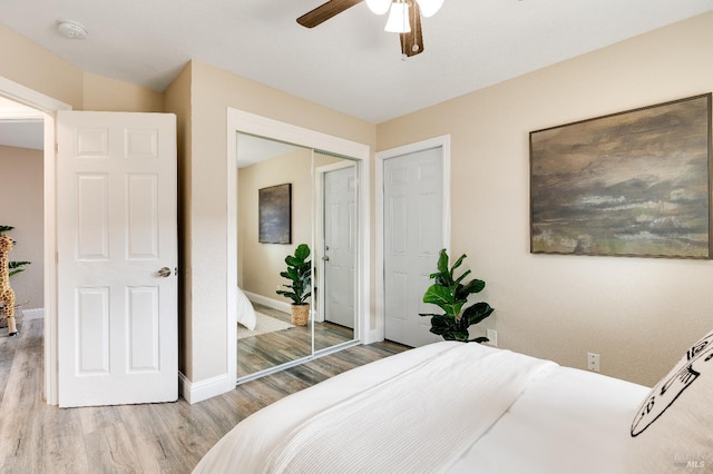 bedroom with a ceiling fan, wood finished floors, baseboards, and a closet
