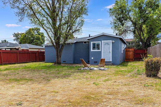 back of property with stucco siding, a fenced backyard, and a lawn