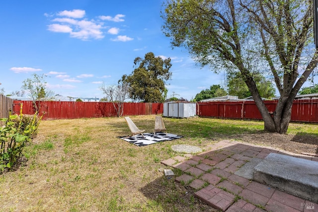 view of yard with a storage shed, a fenced backyard, a patio area, and an outdoor structure