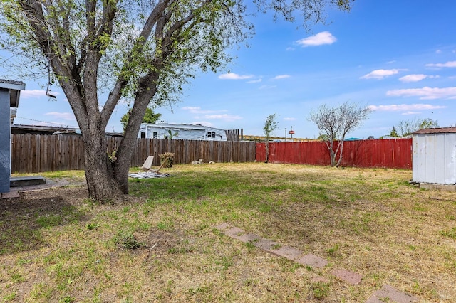 view of yard featuring an outbuilding, a fenced backyard, and a shed