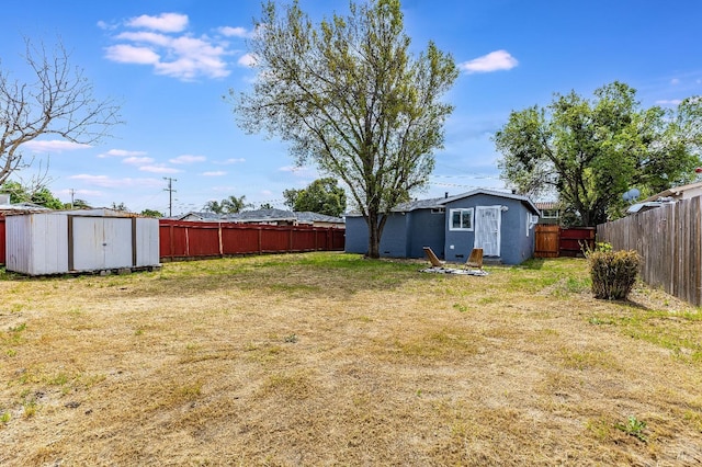 view of yard featuring an outbuilding, a fenced backyard, and a storage unit