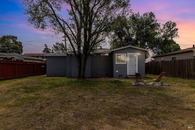 rear view of property with a yard, a fenced backyard, and a fire pit