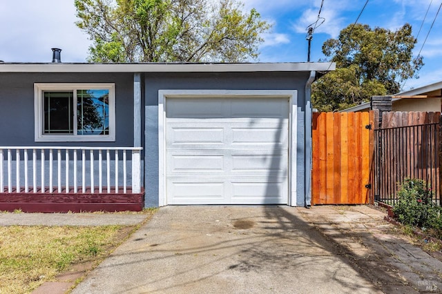 garage featuring fence and concrete driveway