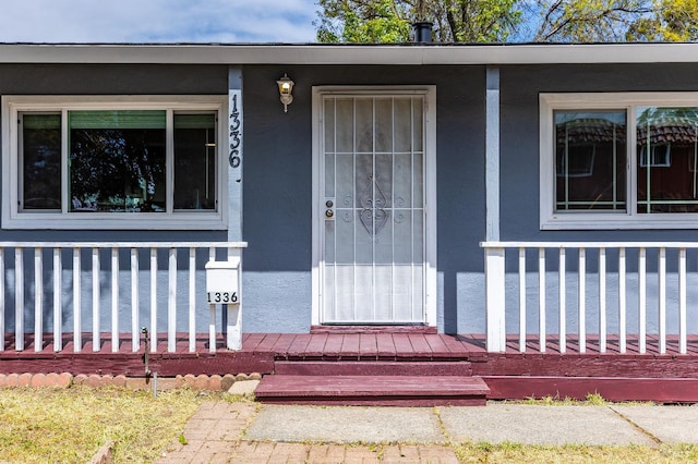 entrance to property featuring stucco siding and a porch