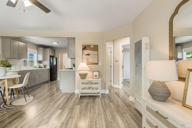 living room featuring ceiling fan, baseboards, a heating unit, and light wood-type flooring