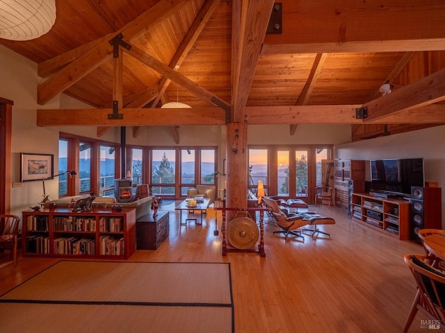 living area with high vaulted ceiling, plenty of natural light, wood ceiling, wood finished floors, and beam ceiling