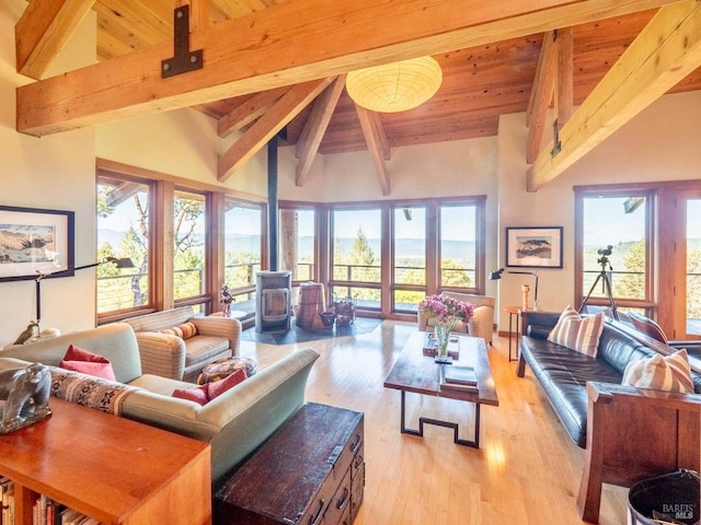 living room featuring beam ceiling, a wood stove, high vaulted ceiling, and light wood-style floors