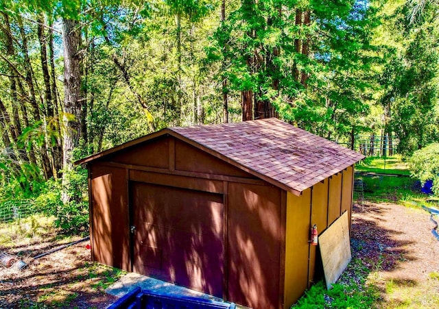 view of outdoor structure featuring a wooded view and an outbuilding