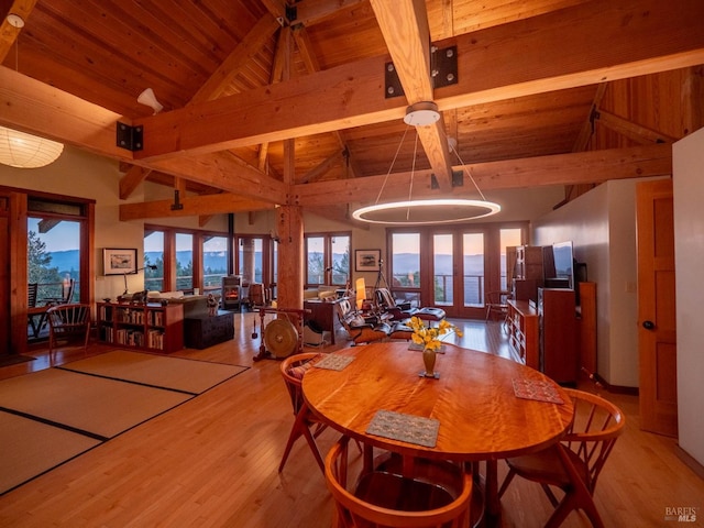 dining space featuring light wood finished floors, wood ceiling, and beam ceiling